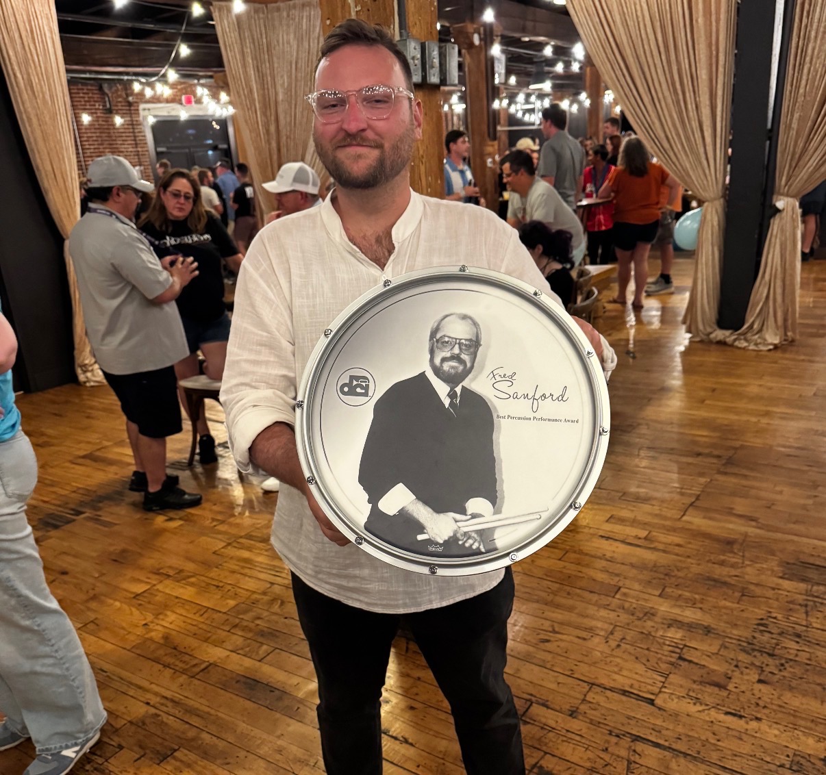 Nick McConnaughey holding a DCI Fred Sanford Best Percussion Performance Award drumhead